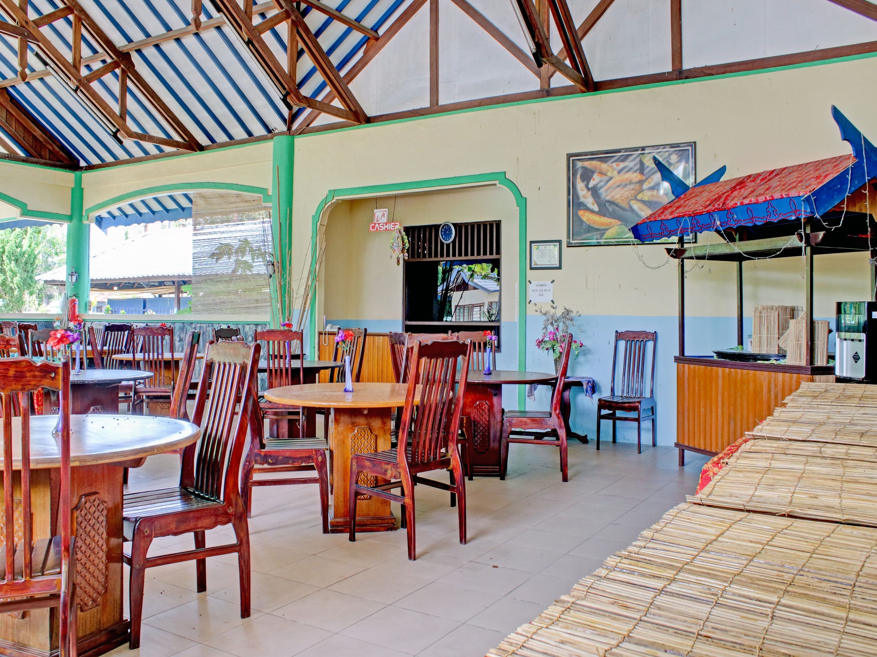 Um restaurante com mesas e cadeiras de madeira, um registo de caixa e um toldo azul.