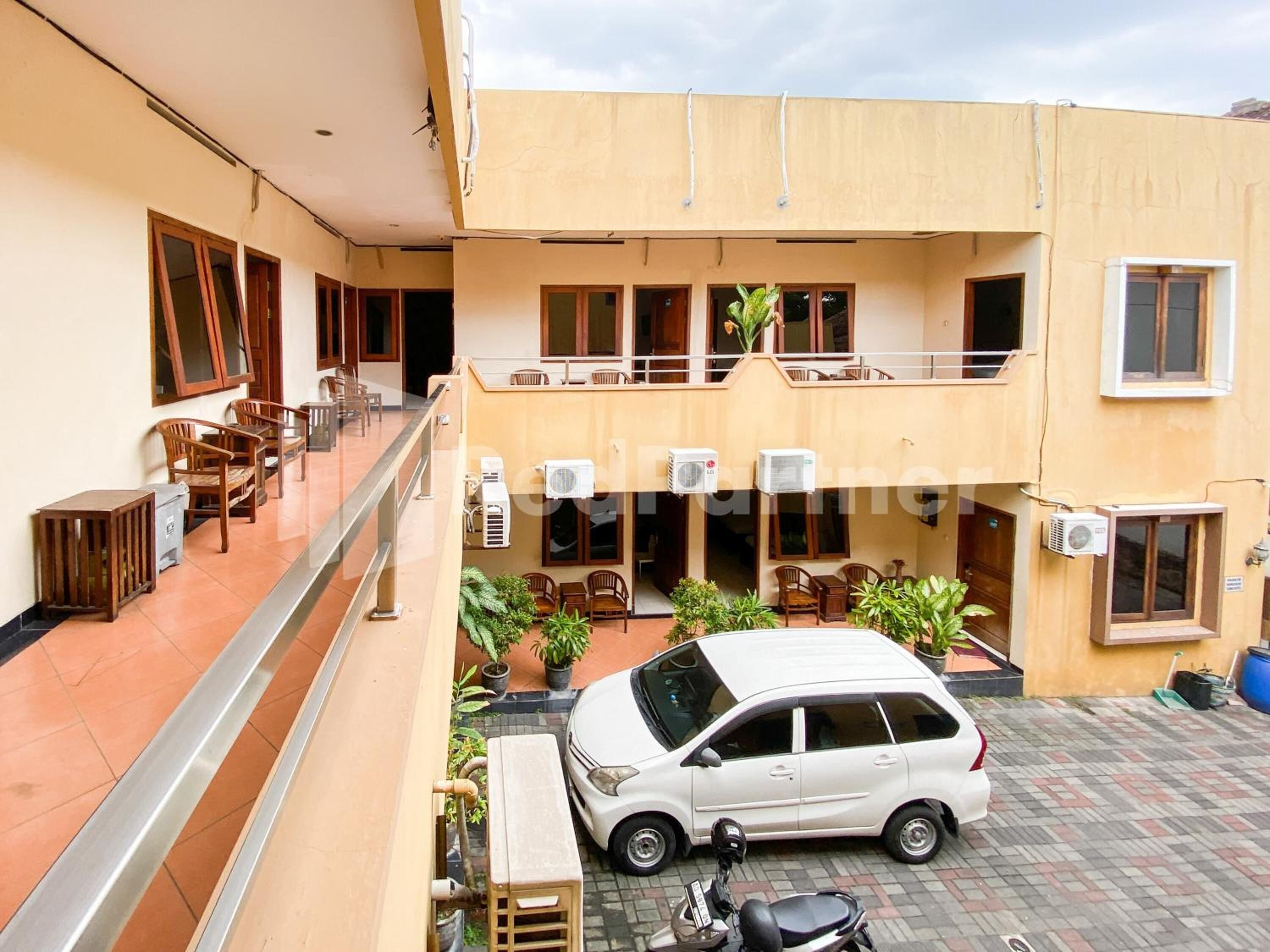 A multi-level building with outdoor seating areas, air conditioning units, and a parked car.