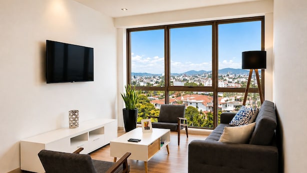 Ein modernes Wohnzimmer mit großem Fenster, Flachbildfernseher, Sofa, Couchtisch und einer Topfpflanze.