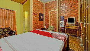 A hotel room with a bed, a television, a small table, a chair, and a wardrobe. - OYO 90031 Villa Papada (Batu)