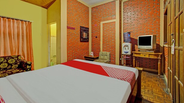 Ein Hotelzimmer mit Bett, Fernseher, kleinem Tisch, Stuhl und Kleiderschrank.