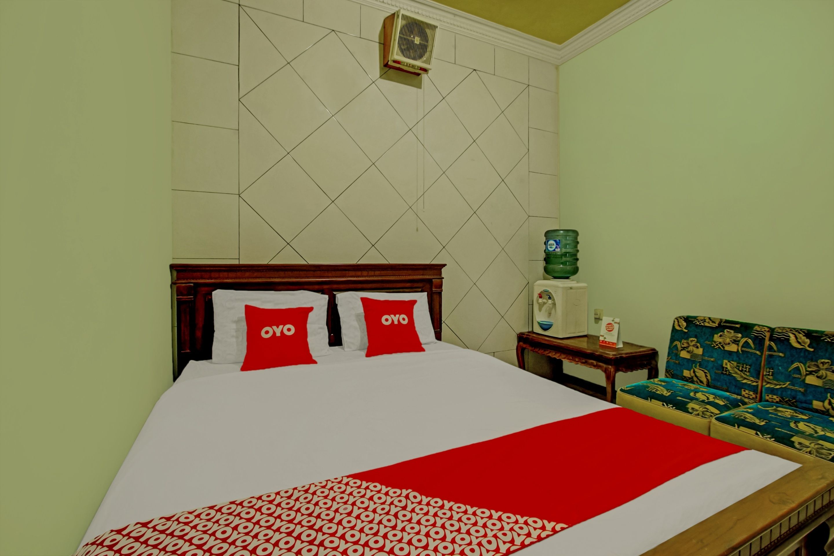 A hotel room with a bed, a water dispenser, and a sofa.