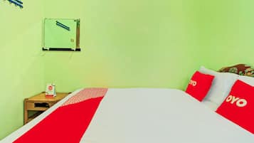 A hotel room with a bed, a nightstand, a wall-mounted air conditioning unit, and a window with a curtain.