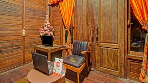 A wooden interior with a desk, laptop, chair, and a door with curtains. - OYO 90031 Villa Papada (Batu)