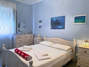 Un dormitorio con cama, cómoda, mesita de noche, espejo y decoración en la pared.