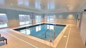 A large indoor swimming pool with clear pool rules and a capacity sign, surrounded by windows and a tiled floor. - Holiday INN EXP White Marsh (WHITE MARSH)