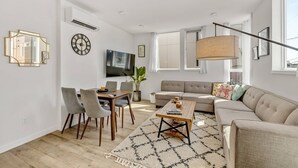 Ein modernes Wohnzimmer mit Sofa, Couchtisch und Essbereich.