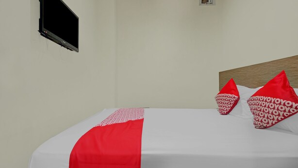Habitació d'hotel amb llit, televisió de pantalla plana penjada a la paret, aire condicionat i una finestra petita.
