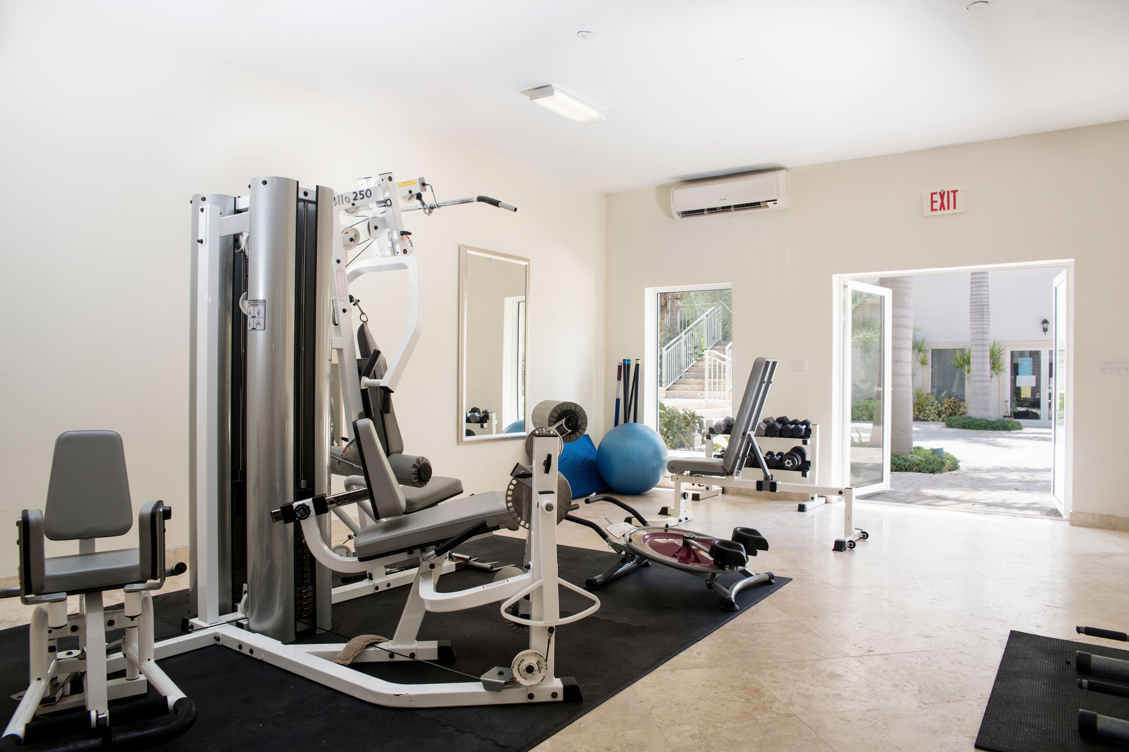 Une salle de sport équipée de divers appareils d’exercice, d’un banc et d’un miroir.