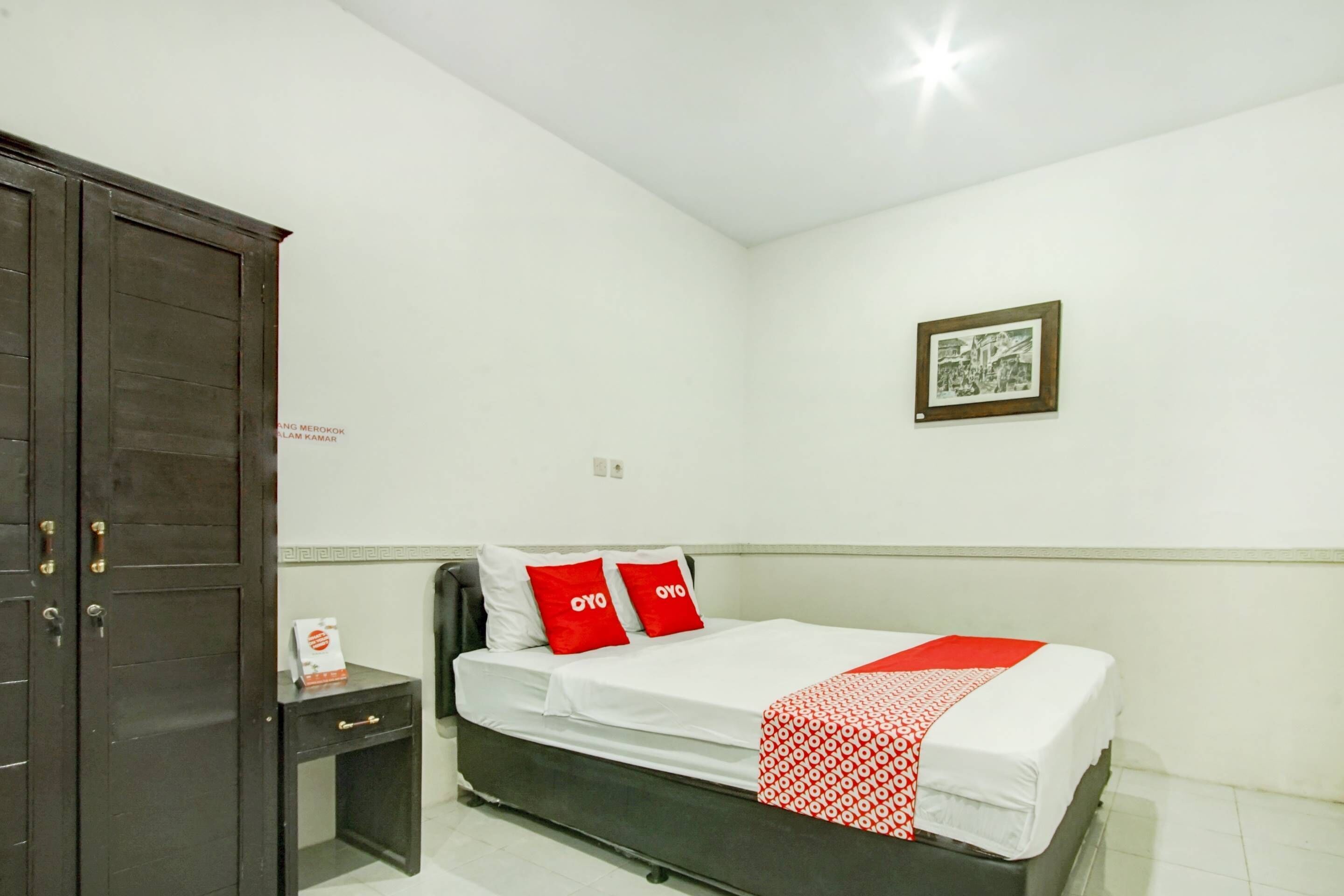 Une chambre à coucher avec un lit, une table de chevet, une armoire et un tableau encadré au mur.