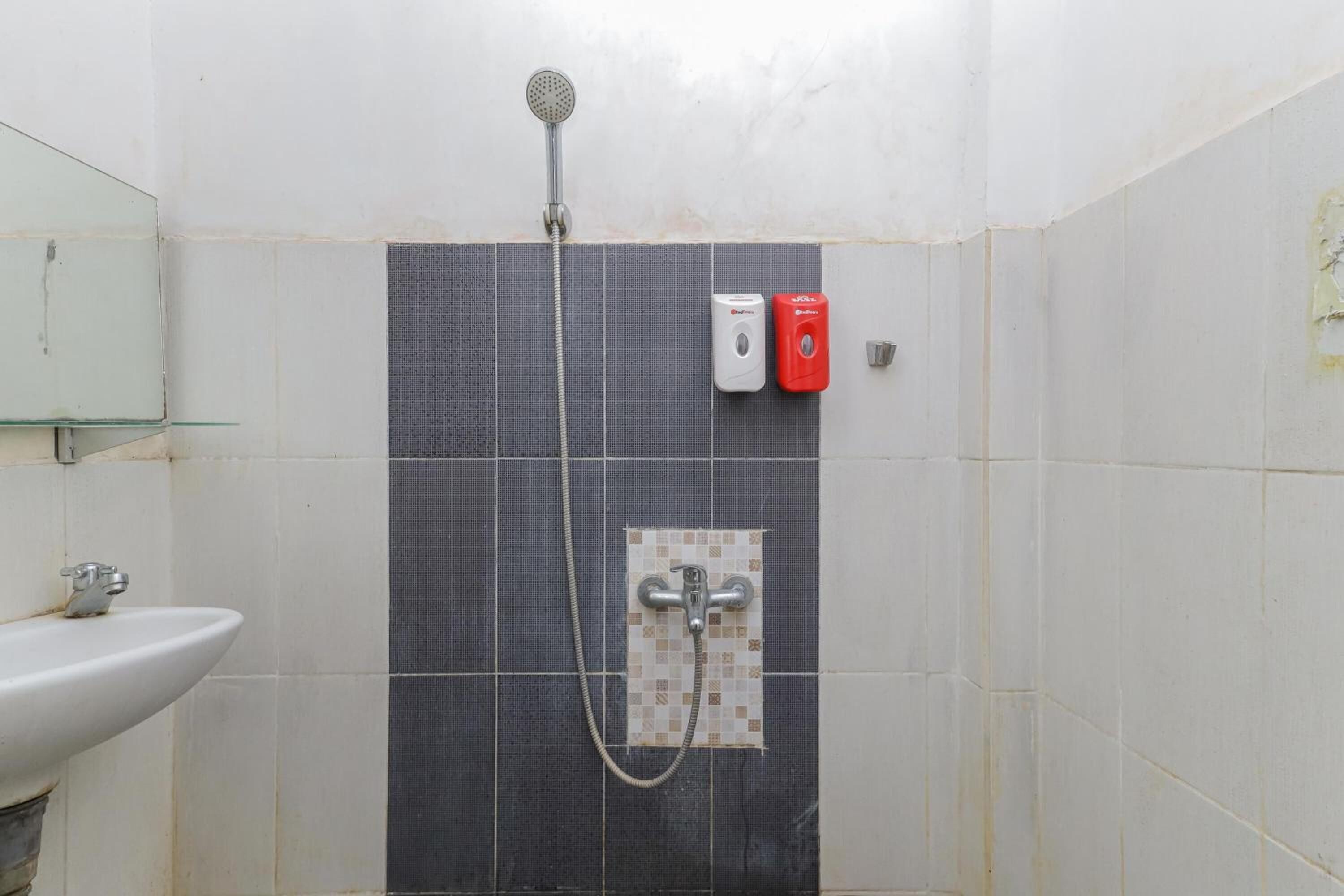 A bathroom with a shower, a sink, and two soap dispensers.
