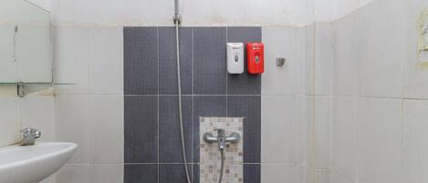 A bathroom with a shower, a sink, and two soap dispensers.