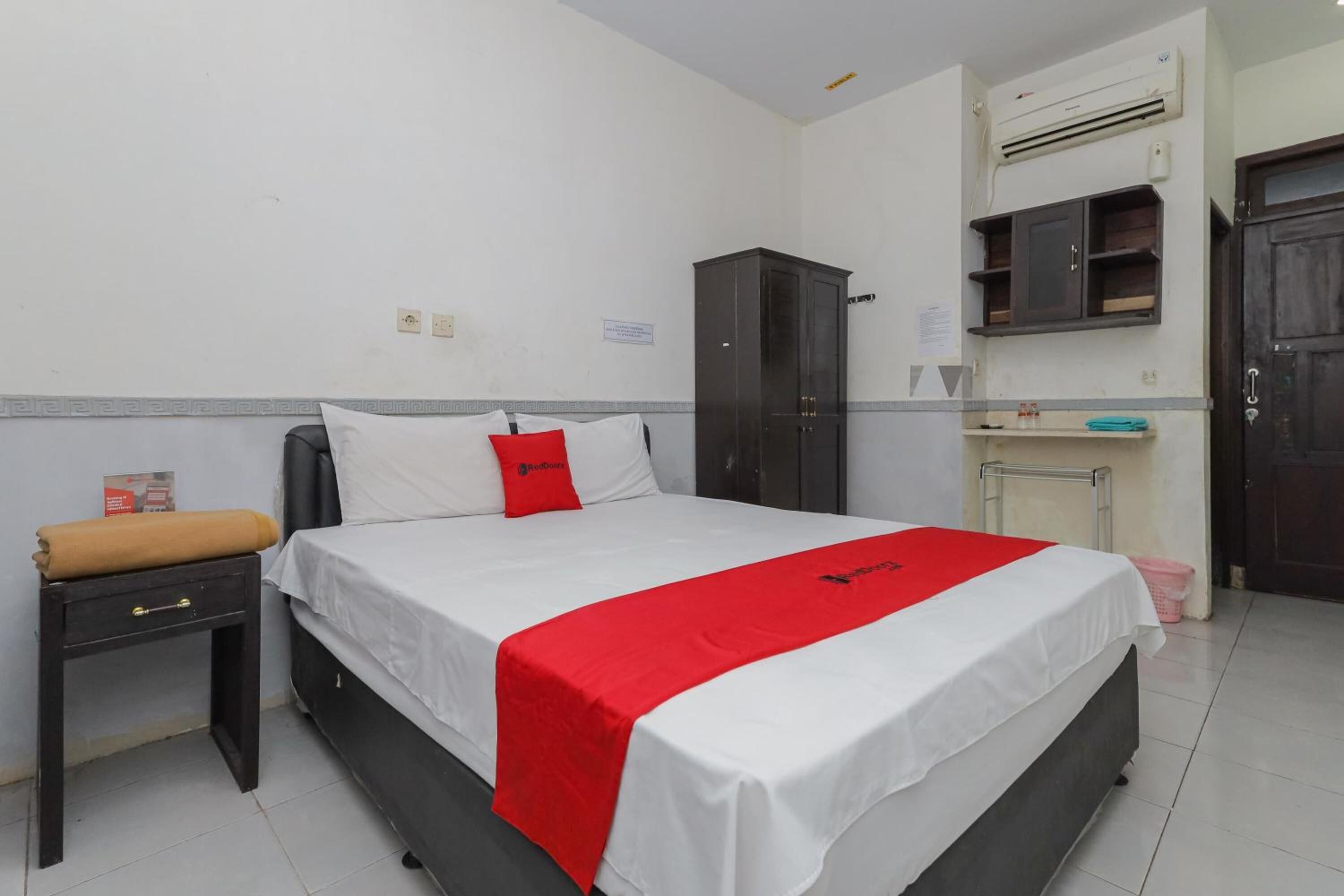 Ein Hotelzimmer mit Bett, kleinem Tisch mit Handtuch, Kleiderschrank und einer Küchenzeile.