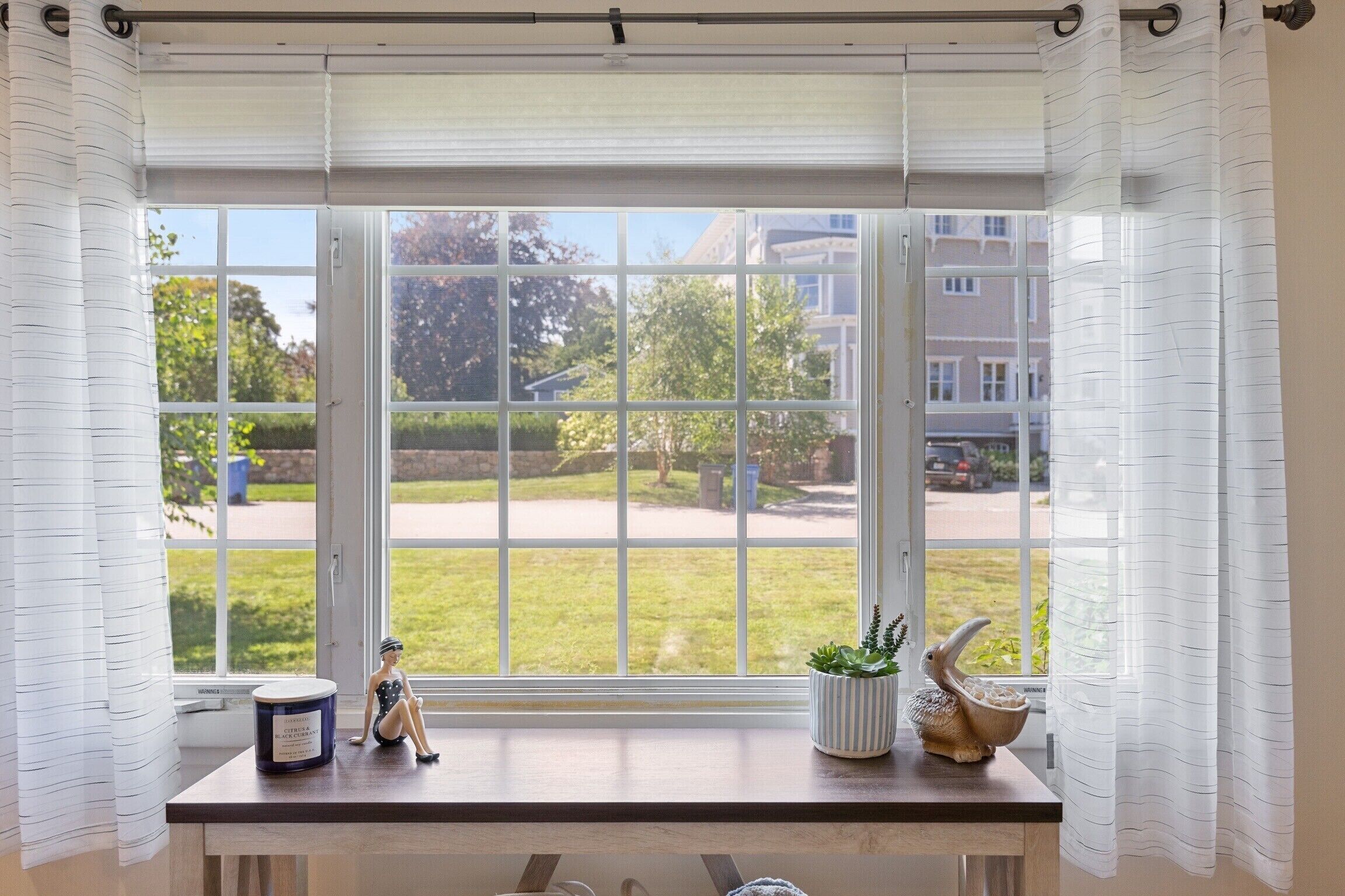 A room with a large window, a wooden desk, a small figurine, and a potted plant.