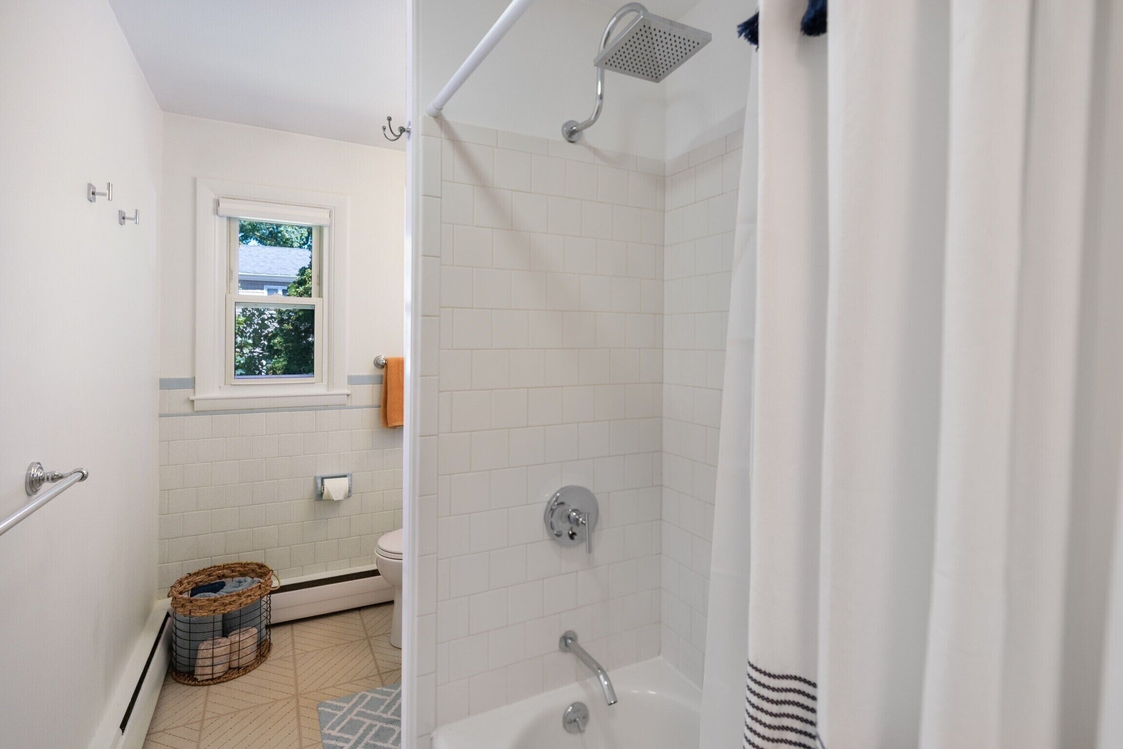 Ein Badezimmer mit Dusche, Toilette und einem Fenster.