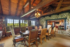Enjoy meals in this inviting dining area with a large wooden table and stone fireplace.