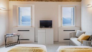 Una habitación con dos camas, un televisor sobre un mueble, y vistas a las montañas a través de las ventanas.