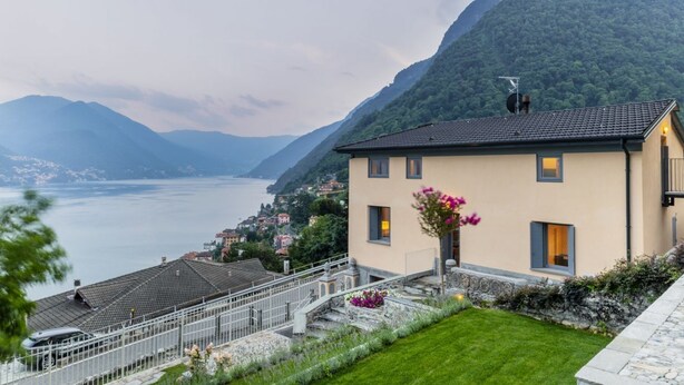 Una casa con balcón que da a un lago y montañas.