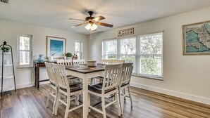 A dining area with a wooden table and chairs, a ceiling fan, and a map on the wall. - Waterfront Home on Canal w/ Dock & Pedal Boat! (Crystal River)