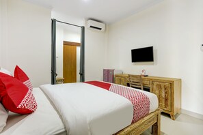 Una habitación de hotel con una cama, un televisor, un armario de madera y un equipo de aire acondicionado.
