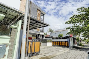 Une maison moderne à deux étages, dotée d’une entrée sécurisée par un portail, d’un balcon et d’une enseigne visible indiquant la présence d’une entreprise.