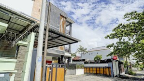 A modern two-story house with a gated entrance, a balcony, and a visible sign for a business. - OYO 90232 March 67 Stay (Denpasar)