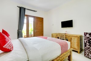 A bedroom with a bed, a wooden dresser, a television on the wall, and a door leading to a balcony. - OYO 90232 March 67 Stay (Denpasar)