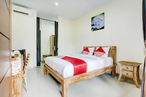 Una habitación de hotel con una cama de madera, una mesita de noche pequeña, un cuadro colgado en la pared y un cartel en la puerta.