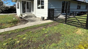 Una casa de un piso con porche delantero, antena parabólica y patio cercado.