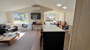 Una sala de estar moderna con una gran mesa de comedor, un sofá y un televisor montado en la pared.