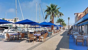 Un puerto deportivo con barcos, asientos al aire libre y un restaurante.