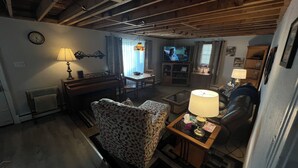 A cozy living room with a sofa, a coffee table, a television, and a piano. - Easy access, roomy, close to so much but in a private country setting. (New Stanton)