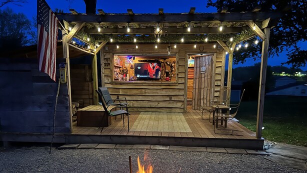 A wooden outdoor seating area with a fire pit, a bar, and a covered patio. - Easy access, roomy, close to so much but in a private country setting. (New Stanton)