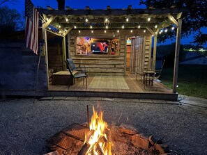Un espace extérieur aménagé en bois, avec un foyer, un bar et une terrasse couverte.