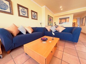 A living room with two blue sofas, a wooden coffee table, and decorative items.