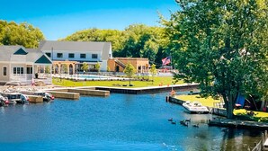 A waterfront property with a dock, boats, and a flag. - Kayak Shack: 1st Floor, Waterfront Lake House, Dock Boat & Jet Ski (Sylvan Beach)