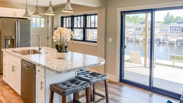 A kitchen with a large island, stainless steel appliances, and a view of a marina through a sliding glass door. - Kayak Shack: 1st Floor, Waterfront Lake House, Dock Boat & Jet Ski (Sylvan Beach)