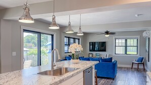 A modern kitchen with a granite countertop, stainless steel sink, and overhead pendant lighting. - Kayak Shack: 1st Floor, Waterfront Lake House, Dock Boat & Jet Ski (Sylvan Beach)