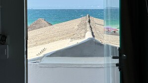 A room with a large window overlooking a beach.