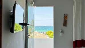 A room with a bed, a TV, and a view of the beach.