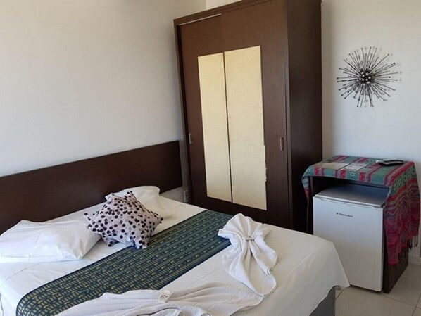 A hotel room with a bed, a wardrobe, a small refrigerator, and a wall decoration. - Thaiji Pousada e Parador (Florianópolis)