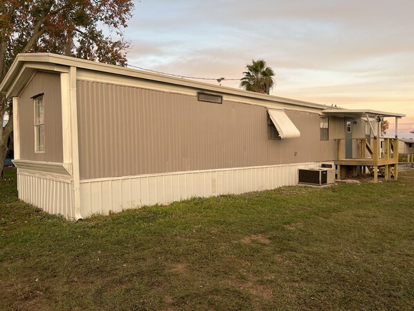 A single-story mobile home with a covered porch and a small deck.