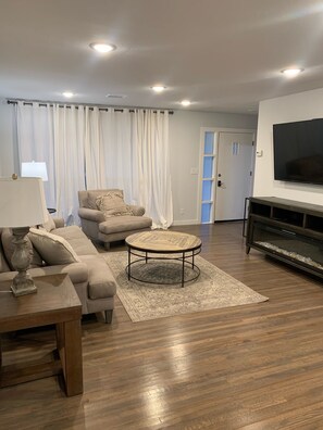 A living room with a sofa, a coffee table, a TV, and a fireplace.