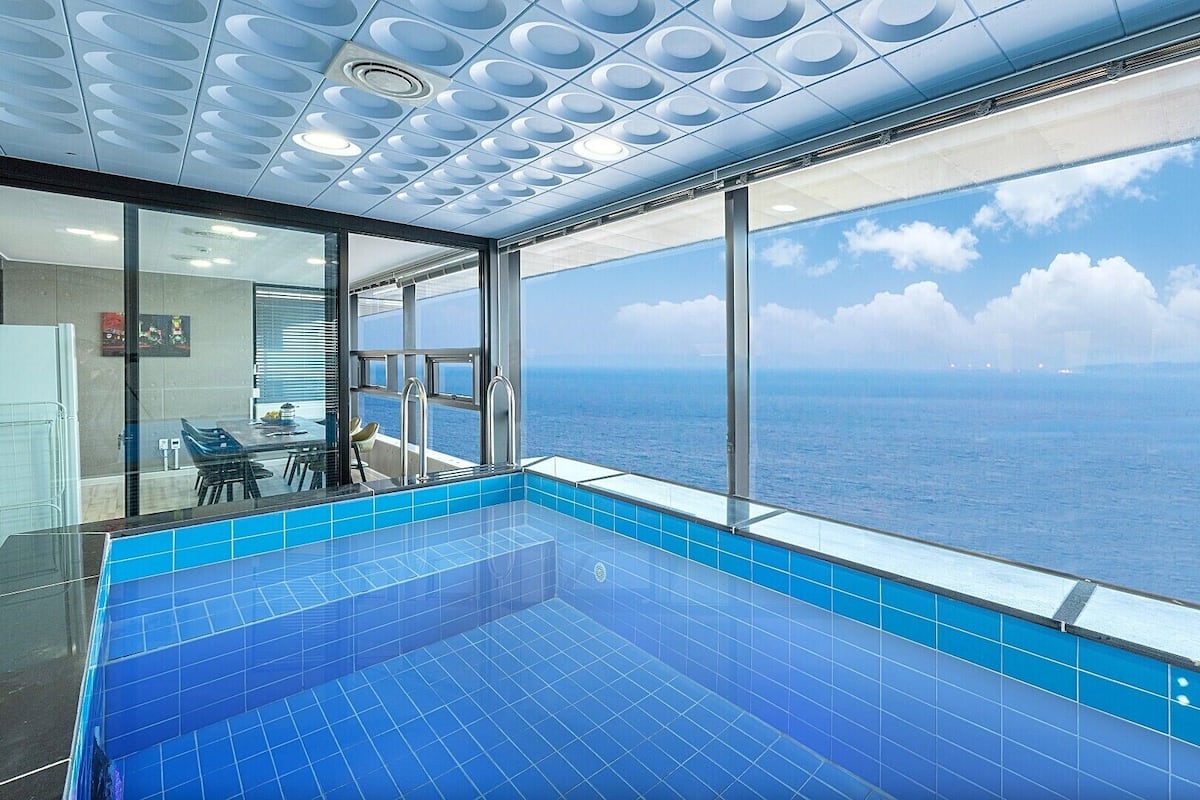 A modern indoor swimming pool with a view of the ocean.