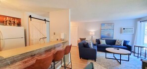 A modern living room with a sofa, coffee table, and a dining area with a bar.