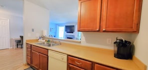 A kitchen with wooden cabinets, a dishwasher, and a coffee maker. - The Hilltop Haven Backs to GTR's Bear Golf Course (Williamsburg)