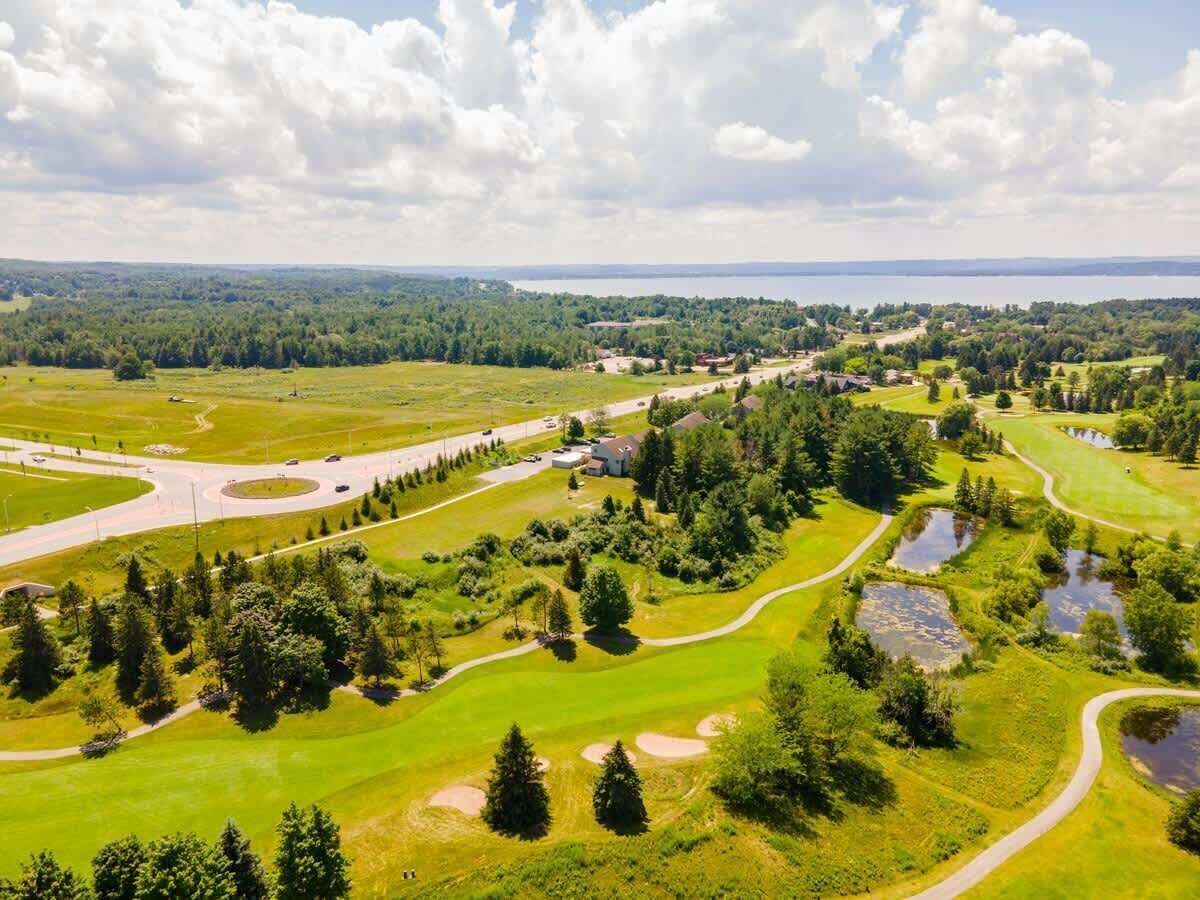 Vista aérea de un campo de golf con un lago al fondo, rodeado de follaje y árboles.