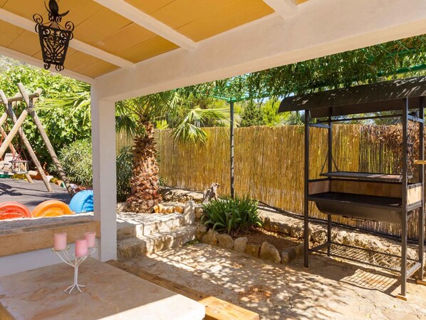 An outdoor patio with a barbecue grill, a swing set, and a decorative lantern.