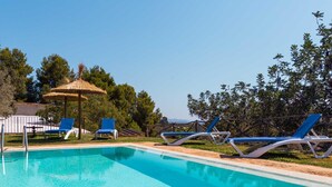 A rectangular swimming pool with clear blue water, surrounded by lounge chairs and a thatched umbrella structure. - Beautiful finca with pool and garden in Biniamar. (Selva)