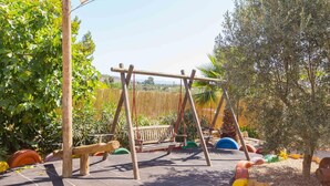 A wooden swing set in a garden with a view of a hilly landscape. - Beautiful finca with pool and garden in Biniamar. (Selva)